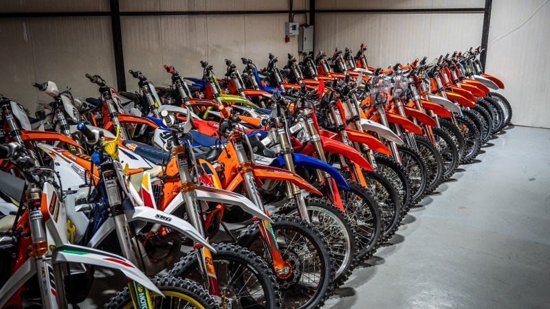 Row of colorful dirt bikes lined up in a storage garage.