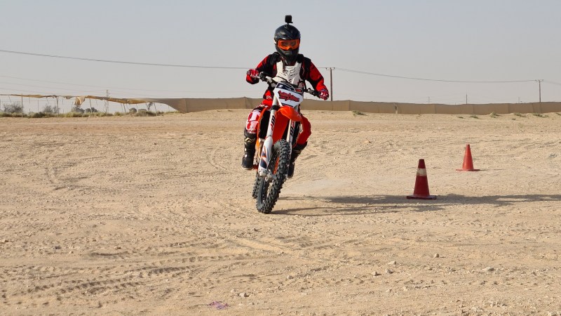 Motorcyclist riding on dirt with traffic cones, wearing protective gear.