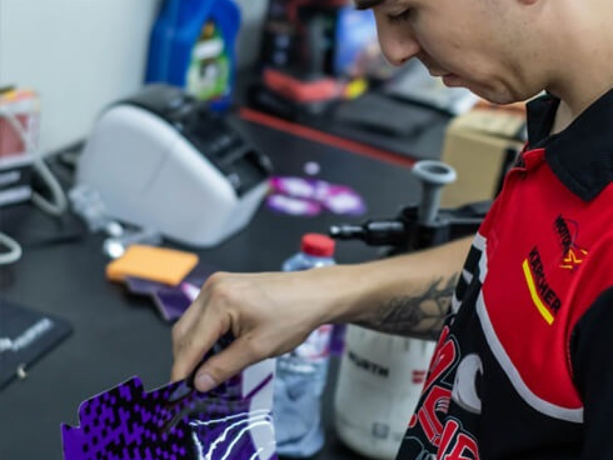 Person applying a purple decal to a smooth surface in a workshop setting.