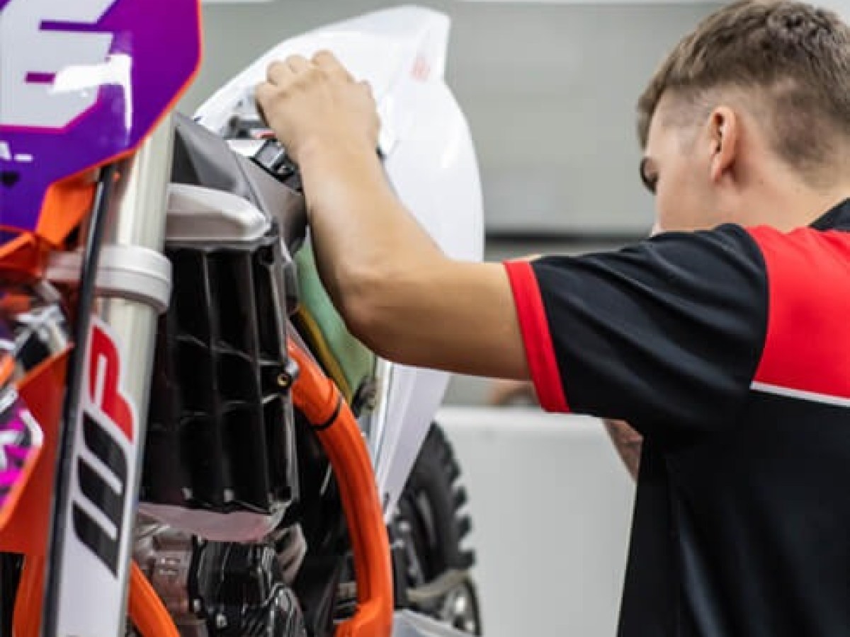 Person working on a dirt bike in a garage setting.