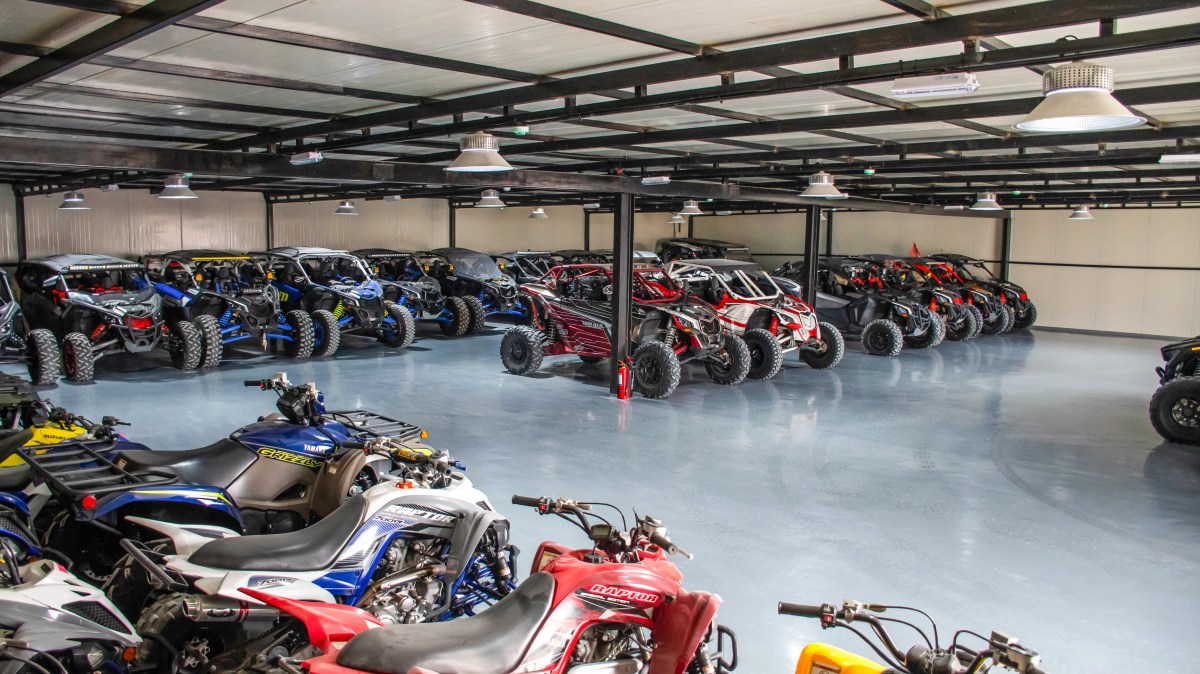 Indoor warehouse storing numerous all-terrain vehicles (ATVs) and side-by-side off-road vehicles.